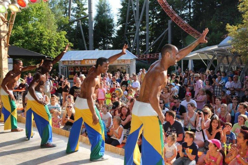 Capoeira-Show im Freizeitpark mit Achterbahn im Hintergrund