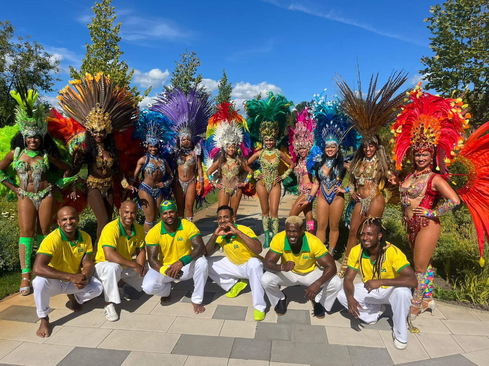 Capoeira-Gruppe in gelben Shirts mit Sambatänzerinnen in einem Garten