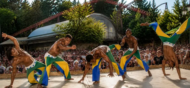 Zwei Capoeira-Künstler im akrobatischen Showkampf auf einer Freiluftbühne vor großem Publikum